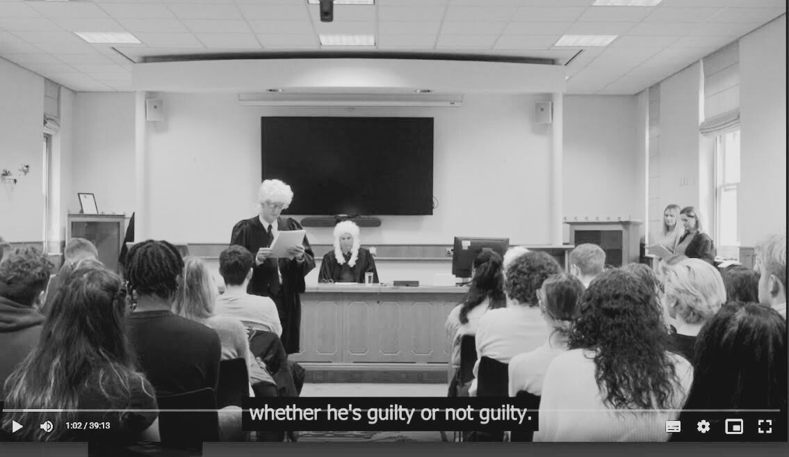 A courtroom with a judge at the front and barrister on his feet